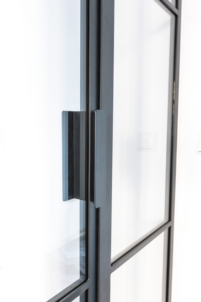 Stahl-Meister Glastrennwand mit Oberlicht, feststehenden Seitenteil und Drehtür, Raumtrenner zwischen Flur, Küche und Wohnzimmer aus Glas in Schwarz, transparentes VSG-Sicherheitsglas, guter Schallschutz, Einbau und Montage in Berlin, Griff, Winkel 40x30x200mm lang