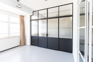 Stahl Lofttür für Gewerbe und Privat, Glastrennwand als Doppel-Schiebetür mit feststehenden Seitenteilen und Oberlicht, individuell hergestellt, Aufmaß und Montage in Berlin, maßgeschneiderter Raumtrenner aus Metall und Glas für Loft-Wohnzimmer und Arbeitsplätze, Aufmaß und Montage, Einbau in Berlin