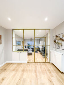 Stahl-Meister Slim Line Loft Tür, Glastrennwand mit goldenem Stahlprofil, Lofttür aus Stahl und Glas, mit Drehtür, Oberlicht und Seitenteil im Wohnzimmer und Küche, Glaskonstruktion, Verbindung von Seitenteilen, aufgesetzte Glassprossen aus Aluminium