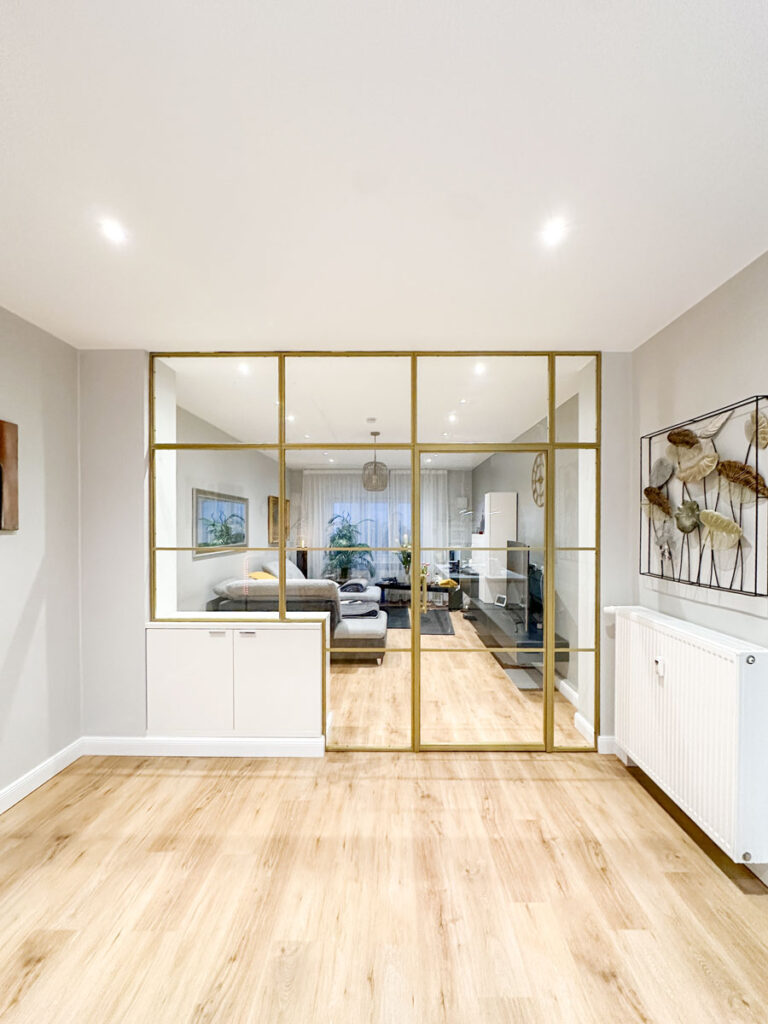 Stahl-Meister Slim Line Loft Tür, Glastrennwand mit goldenem Stahlprofil, Lofttür aus Stahl und Glas, mit Drehtür, Oberlicht und Seitenteil im Wohnzimmer und Küche, Glaskonstruktion, Verbindung von Seitenteilen, aufgesetzte Glassprossen aus Aluminium