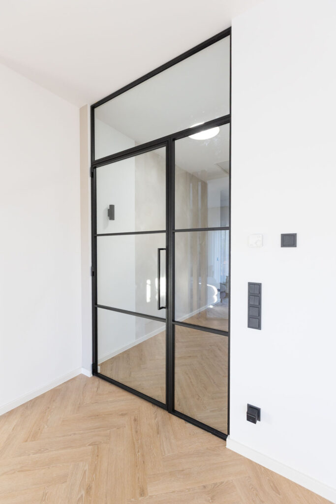 Stahl_Meister_Slim_Line_Lofttuer_Glastrennwand_Stahlrahmen_Glas_Drehtuer_Oberlicht_Seitenteil_Schwarz_826A3933 Stahl-Meister - günstige Slim Line Loft Tür, Glastrennwand mit Drehtür, Seitenteil und Oberlicht, schwarzem Stahlprofil, Lofttür aus Stahl und Glas, als Schallschutz und Wärmedämmung zwischen Flur und Wohnzimmer und Arbeitszimmer filigrane Tür mit RAL 9005 Tiefschwarz Stahlrahmen und Klarglas Glas